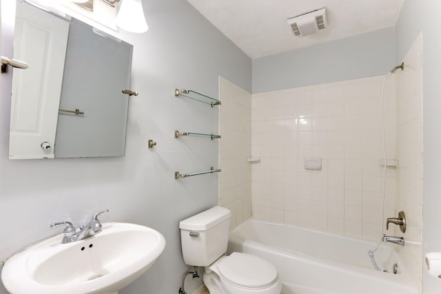 full bathroom featuring tiled shower / bath, toilet, sink, and a textured ceiling