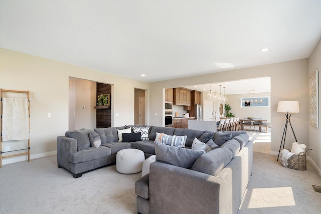 living room featuring sink, light carpet, and a notable chandelier