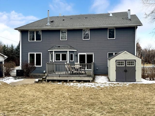 rear view of property with a wooden deck, central AC, a lawn, and a storage shed