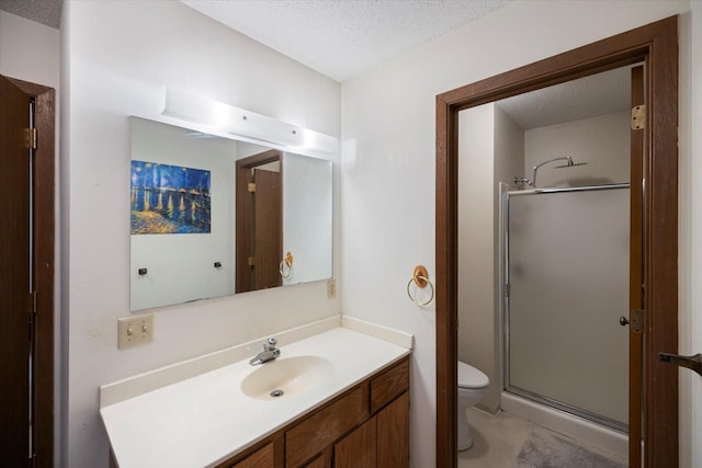 bathroom featuring vanity, a textured ceiling, a shower with shower door, and toilet