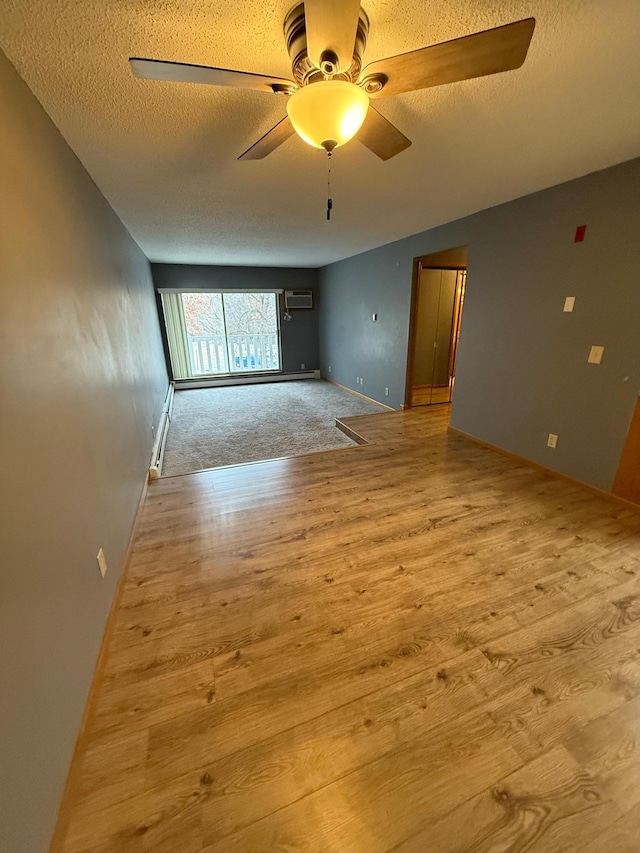 unfurnished room with ceiling fan, light hardwood / wood-style flooring, a wall mounted AC, and a textured ceiling