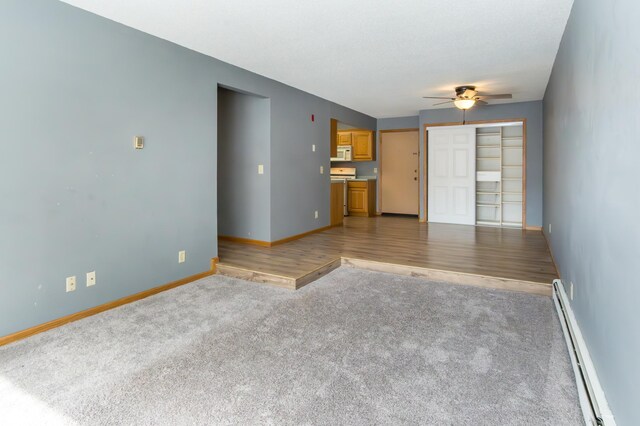 unfurnished living room featuring a baseboard heating unit, ceiling fan, light carpet, and baseboards