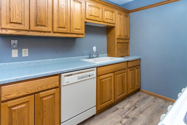 kitchen featuring baseboards, dishwasher, light wood-style flooring, light countertops, and a sink