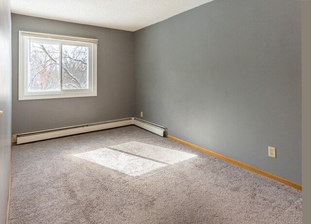 empty room with a textured ceiling, baseboard heating, carpet flooring, and baseboards