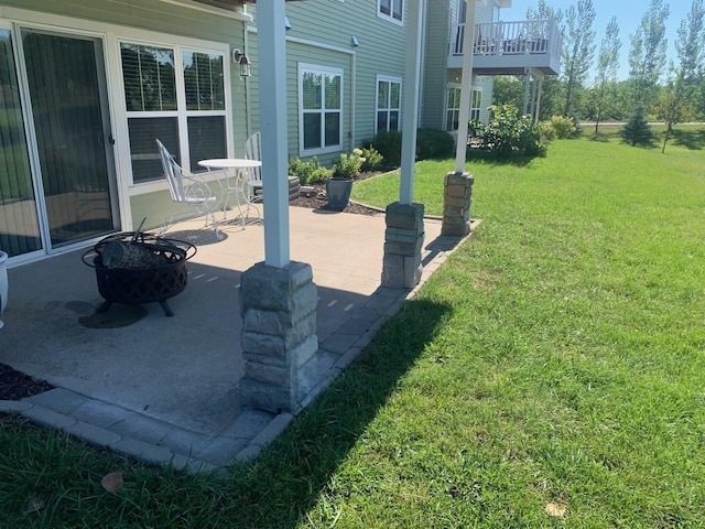 view of yard featuring a fire pit, a patio area, and a balcony