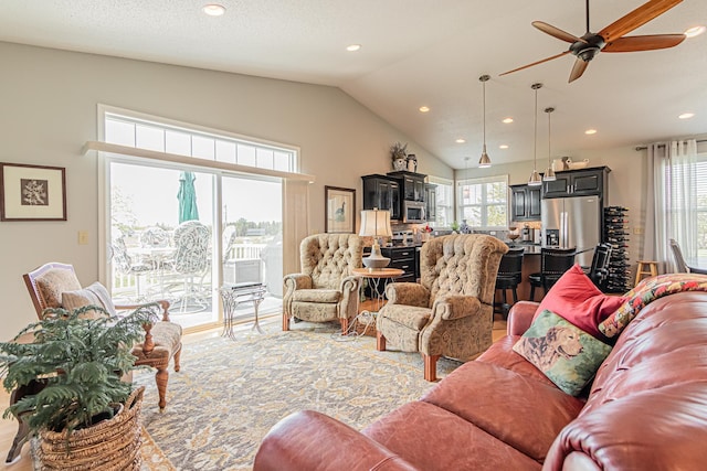 living room featuring ceiling fan, lofted ceiling, a healthy amount of sunlight, and a textured ceiling