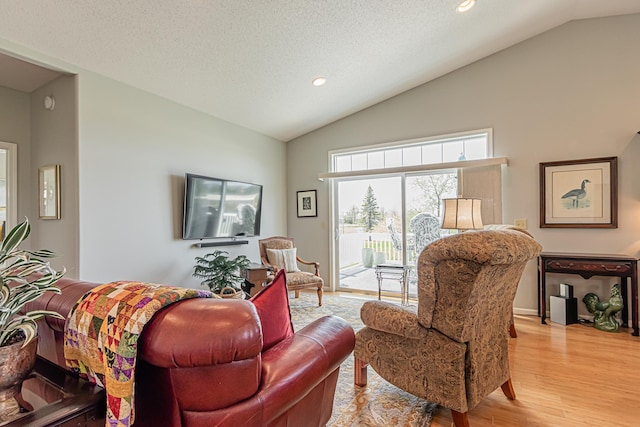 living room with vaulted ceiling, light hardwood / wood-style flooring, and a textured ceiling