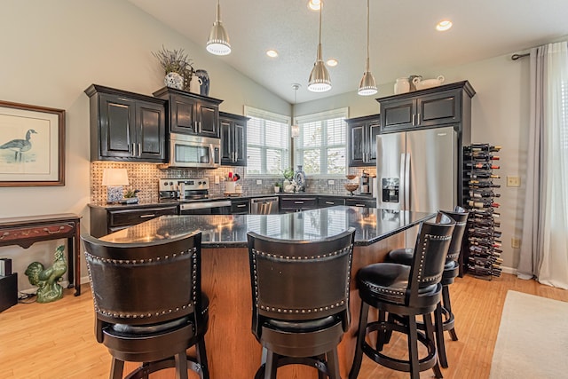 kitchen featuring appliances with stainless steel finishes, a center island, pendant lighting, and a breakfast bar