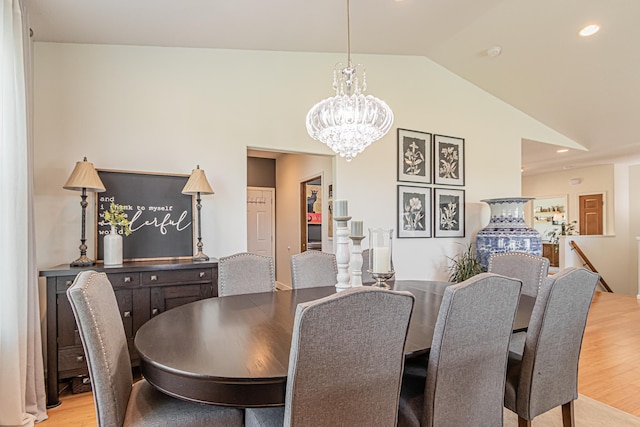 dining space with lofted ceiling, light hardwood / wood-style flooring, and a chandelier