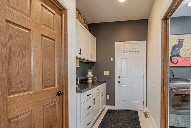 interior space with washer / clothes dryer, light tile patterned floors, and cabinets