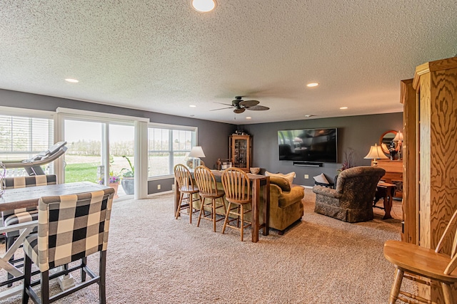 carpeted living room featuring ceiling fan and a textured ceiling