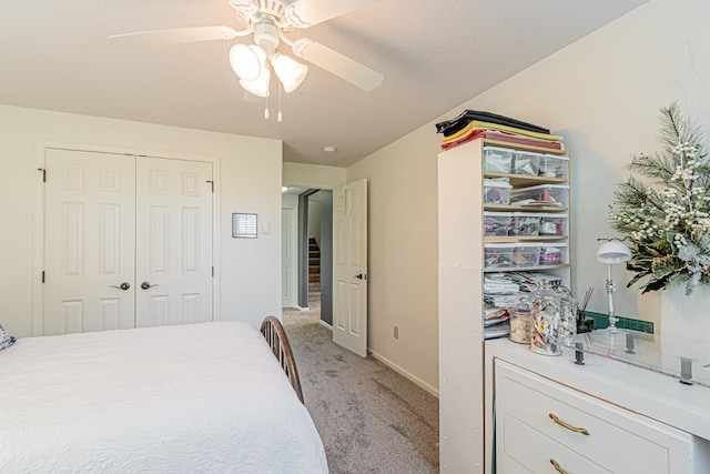 bedroom featuring a textured ceiling, light colored carpet, a closet, and ceiling fan