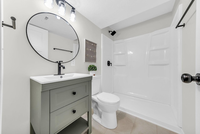 bathroom featuring tile patterned flooring, vanity, toilet, and walk in shower