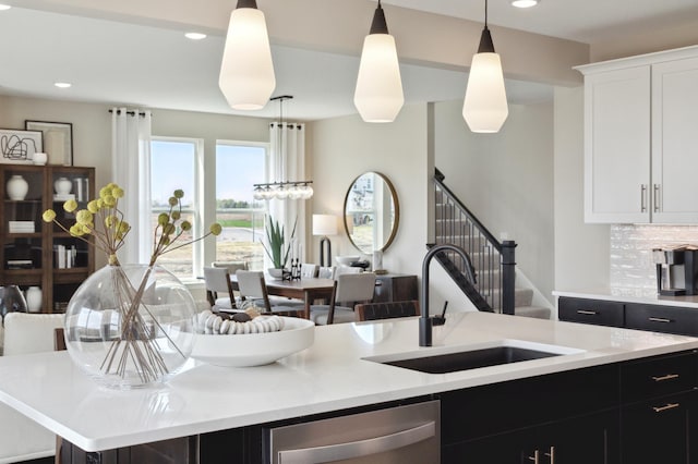 kitchen featuring sink, decorative light fixtures, stainless steel dishwasher, a kitchen island with sink, and backsplash