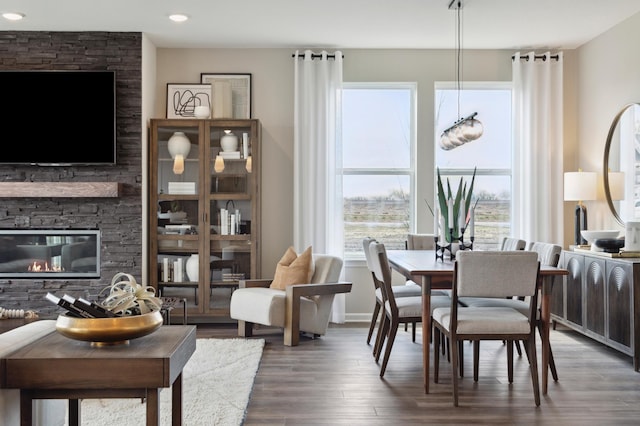 dining space featuring a stone fireplace and dark hardwood / wood-style flooring