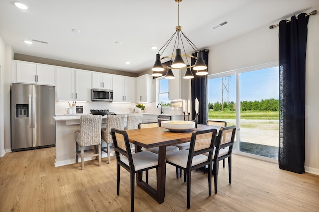 dining space with a notable chandelier and light hardwood / wood-style floors