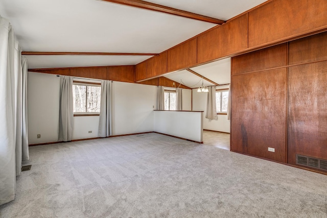 unfurnished room featuring light carpet, vaulted ceiling with beams, and a notable chandelier