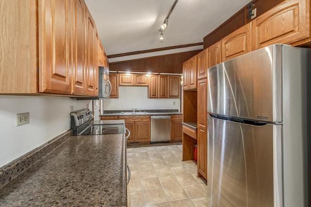 kitchen with lofted ceiling, sink, light tile patterned floors, appliances with stainless steel finishes, and track lighting