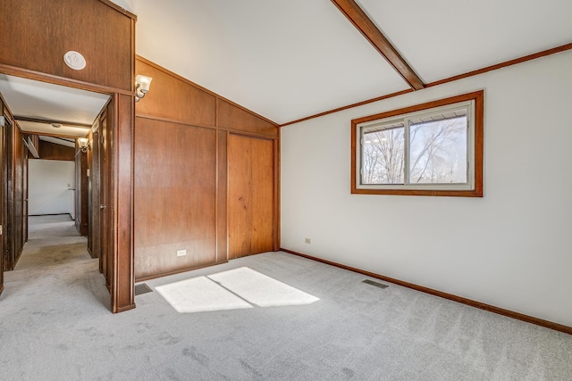 unfurnished bedroom with lofted ceiling with beams, crown molding, light carpet, and a closet