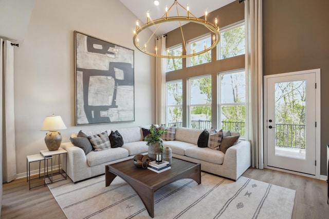 living room featuring a high ceiling, a chandelier, and light wood-type flooring