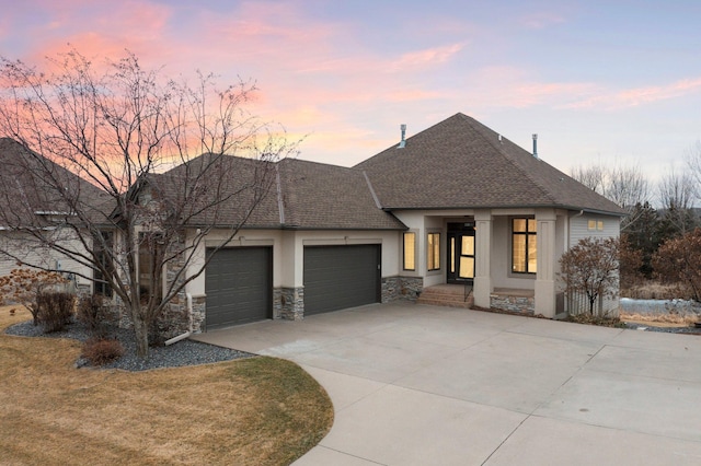 view of front facade with an attached garage, stone siding, driveway, roof with shingles, and stucco siding