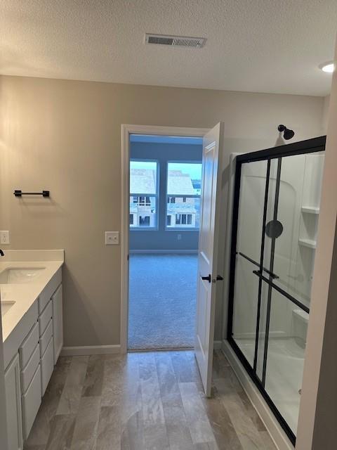 bathroom with vanity, an enclosed shower, and a textured ceiling