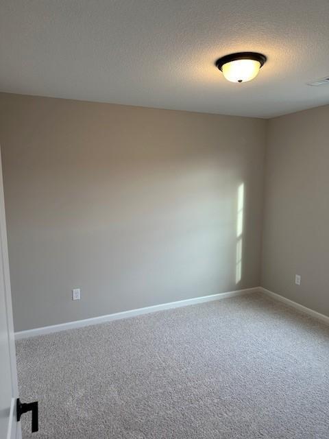 carpeted spare room with a textured ceiling