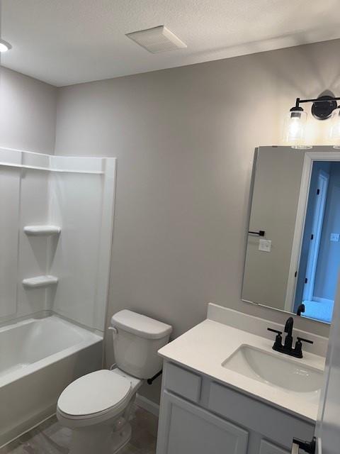 full bathroom featuring vanity, toilet,  shower combination, and a textured ceiling