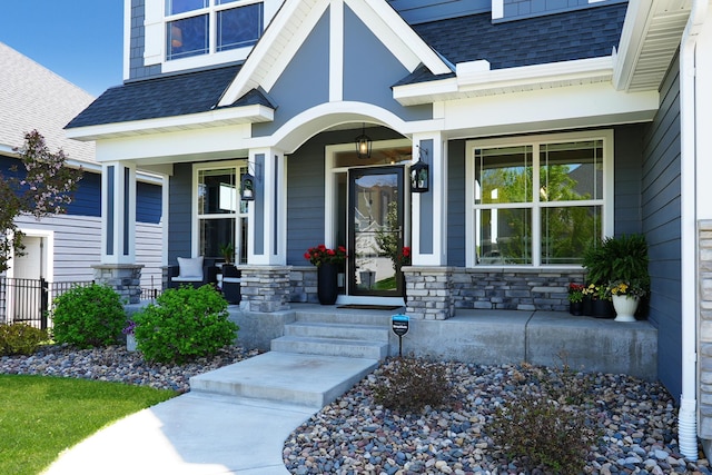 13157 Coral Sea Ct NE, Blaine, MN 55449 - property entrance featuring a porch, a shingled roof, and stone siding