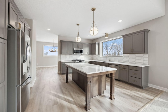 kitchen featuring a kitchen island, appliances with stainless steel finishes, pendant lighting, tasteful backsplash, and a kitchen breakfast bar