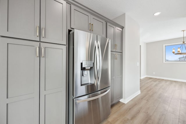 kitchen featuring gray cabinets, hanging light fixtures, a notable chandelier, light hardwood / wood-style floors, and stainless steel fridge with ice dispenser