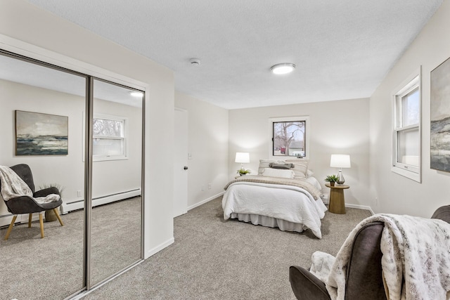 carpeted bedroom featuring a textured ceiling, baseboard heating, and a closet