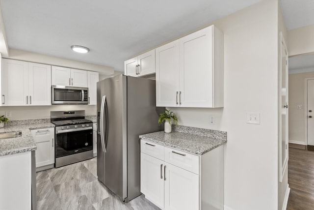 kitchen featuring light stone counters, appliances with stainless steel finishes, and white cabinets