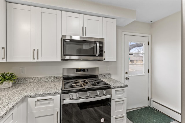 kitchen with light stone countertops, white cabinetry, appliances with stainless steel finishes, and a baseboard heating unit