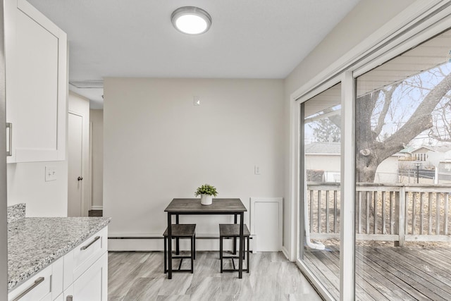 kitchen with light stone counters, light hardwood / wood-style flooring, and white cabinets