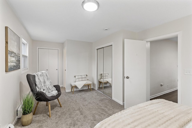 carpeted bedroom with multiple closets and baseboard heating