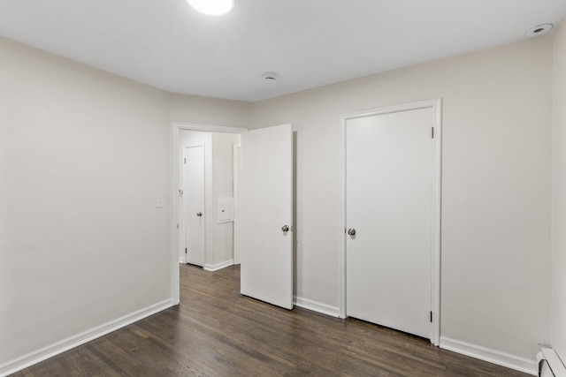 unfurnished bedroom featuring a baseboard radiator and dark wood-type flooring