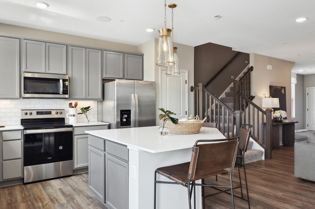 kitchen with stainless steel appliances, decorative light fixtures, a center island, and gray cabinetry