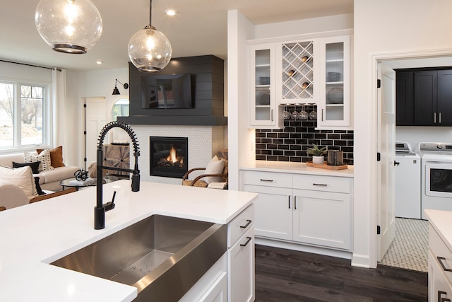 kitchen featuring sink, dark wood-type flooring, independent washer and dryer, white cabinets, and decorative light fixtures