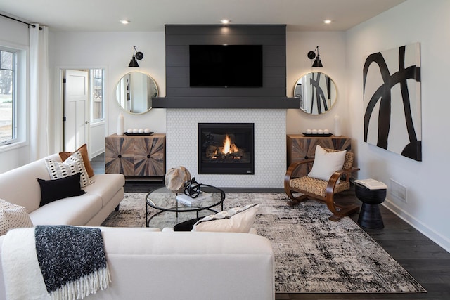 living room featuring a tiled fireplace and hardwood / wood-style flooring