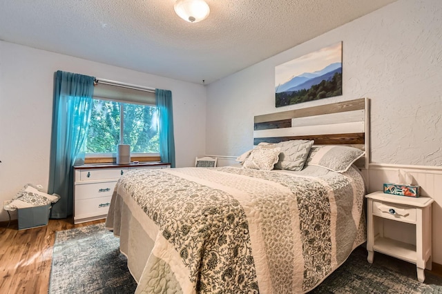 11132 100th Pl N, Maple Grove, MN 55369 - bedroom with a textured ceiling, wood finished floors, and wainscoting
