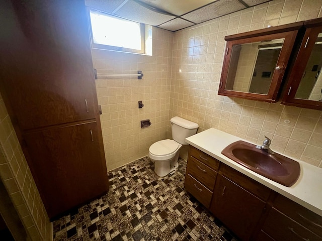 bathroom featuring vanity, tile walls, and toilet