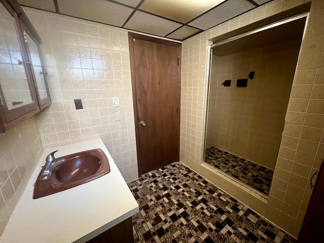 bathroom with vanity, tile walls, a drop ceiling, and walk in shower