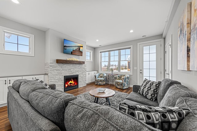 living room with dark hardwood / wood-style flooring and a stone fireplace