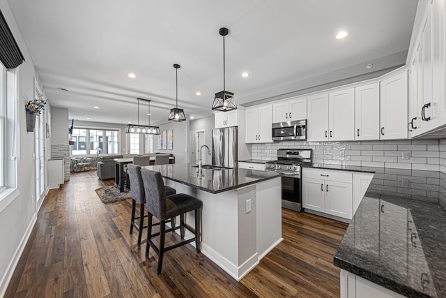 kitchen with dark wood-type flooring, appliances with stainless steel finishes, open floor plan, and white cabinets