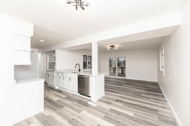 kitchen featuring sink, white cabinetry, light hardwood / wood-style floors, stainless steel dishwasher, and kitchen peninsula