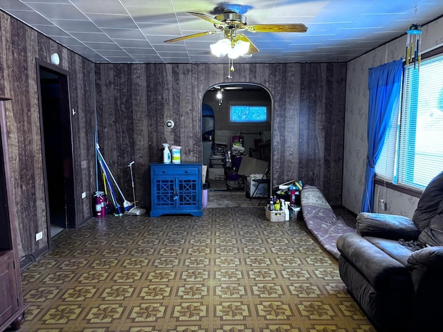 interior space featuring ceiling fan and wood walls