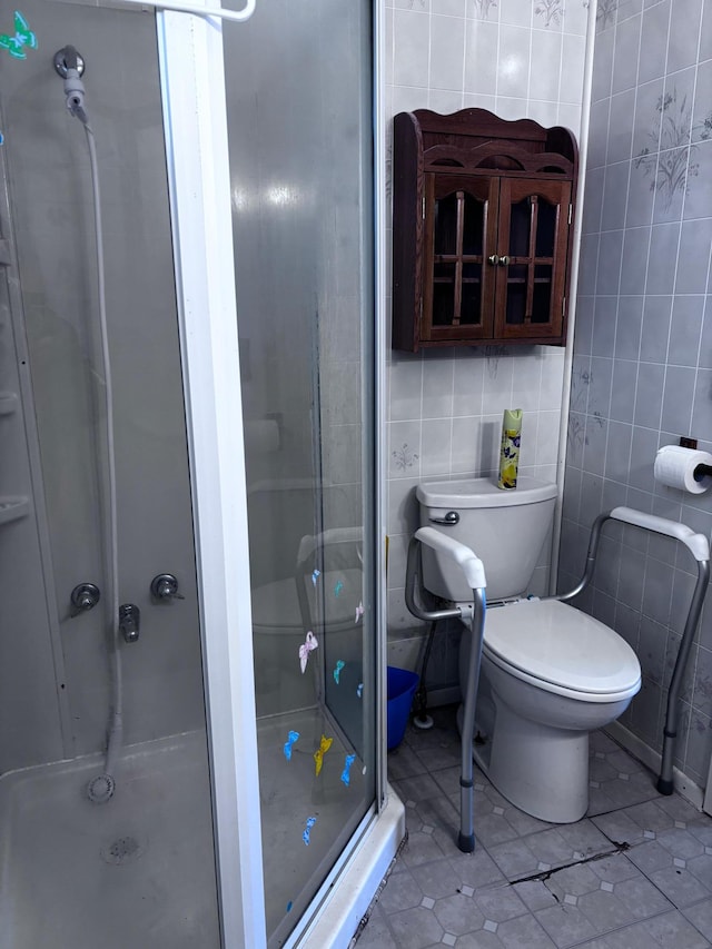 bathroom with toilet, an enclosed shower, tile patterned flooring, and tile walls