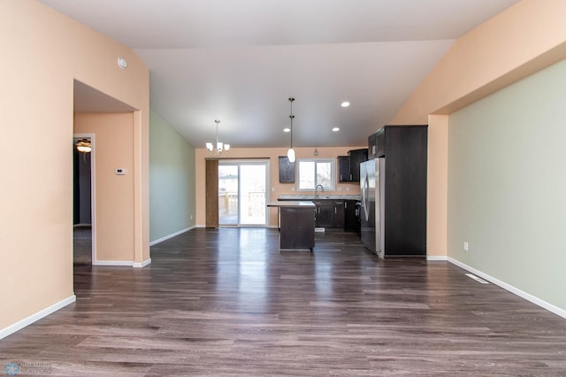 kitchen featuring lofted ceiling, light countertops, freestanding refrigerator, open floor plan, and a kitchen island