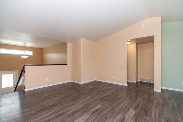 empty room with baseboards, visible vents, vaulted ceiling, and dark wood-style flooring